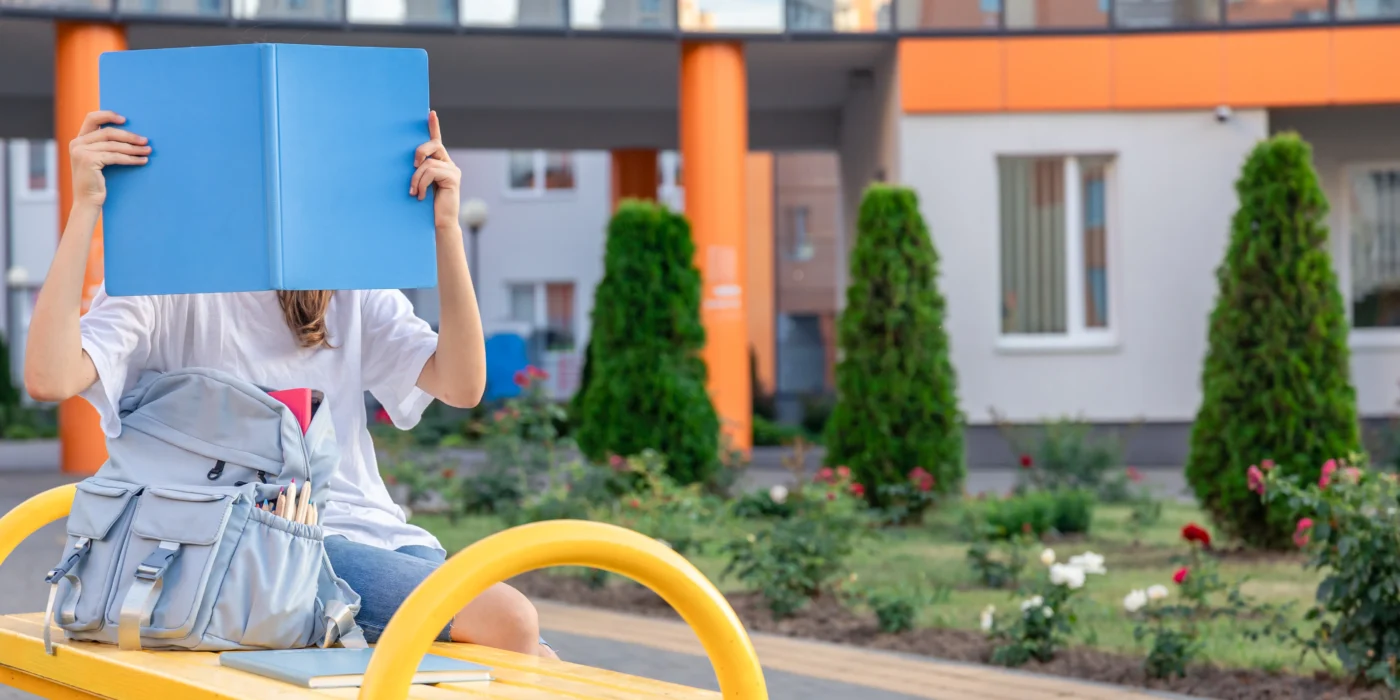girl-with-blue-notebook-covers-her-face-background-school