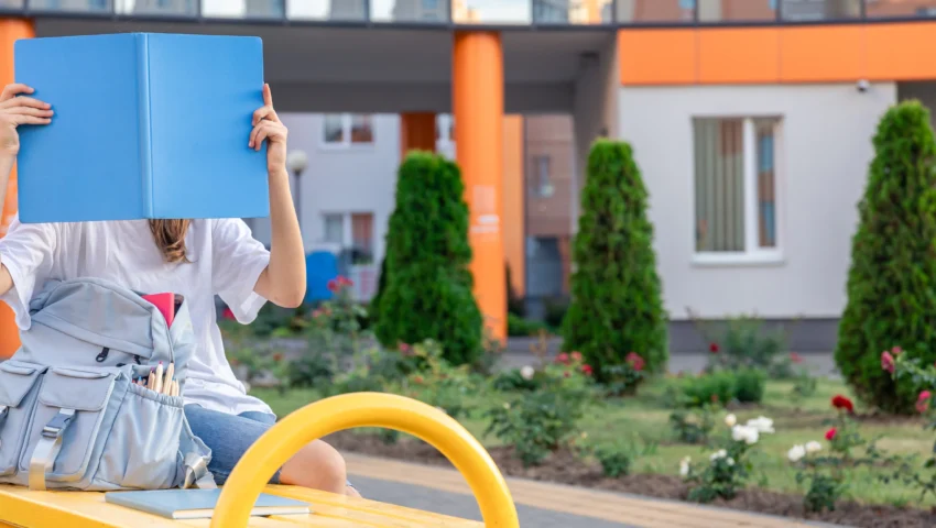 girl-with-blue-notebook-covers-her-face-background-school