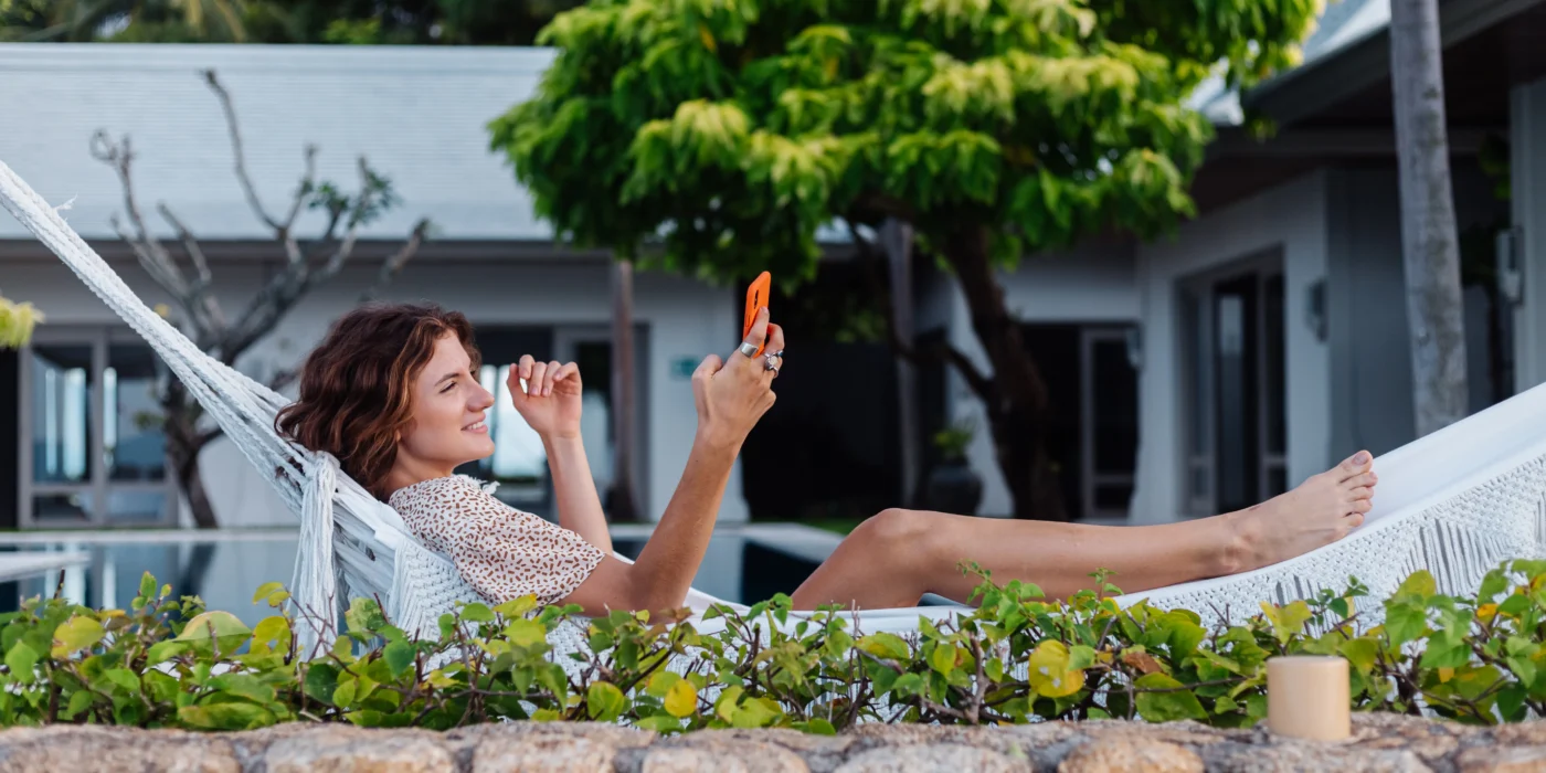 woman-with-phone-resting-lying-hammock-with-mobile-phone-scaled