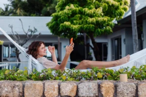 woman-with-phone-resting-lying-hammock-with-mobile-phone-scaled