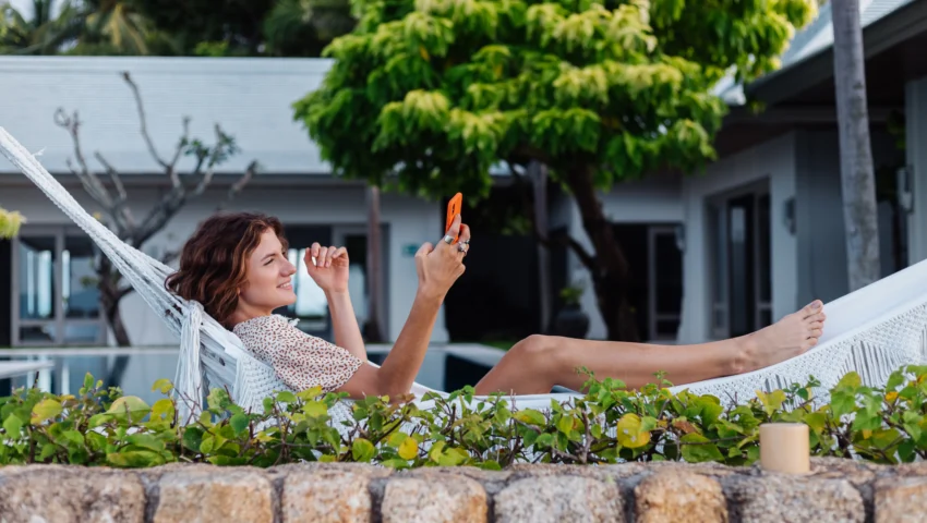 woman-with-phone-resting-lying-hammock-with-mobile-phone-scaled